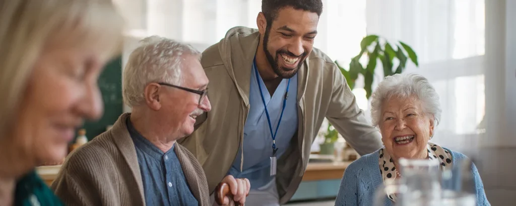A nurse coming to seniors sitting together laughing and talking