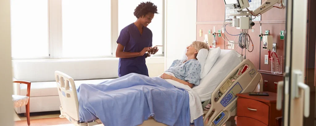 a nursing talking to an elderly patient in a hospital bed